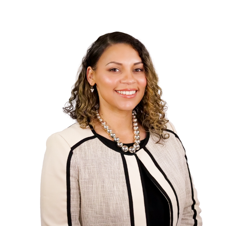 Woman with shoulder-length curly hair, wearing a cream and black jacket with a pearl necklace, smiling in front of a white background.