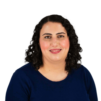 Woman with shoulder-length dark curly hair, wearing a navy blue top, smiling gently in front of a white background.