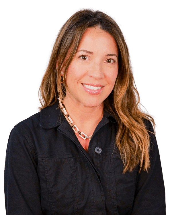 Woman with long wavy hair, wearing a black zip-up jacket and a chunky chain necklace, smiling against a white background.