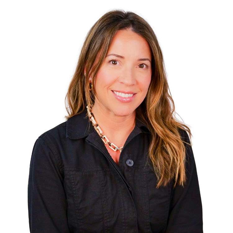 Woman with long wavy hair, wearing a black zip-up jacket and a chunky chain necklace, smiling against a white background.