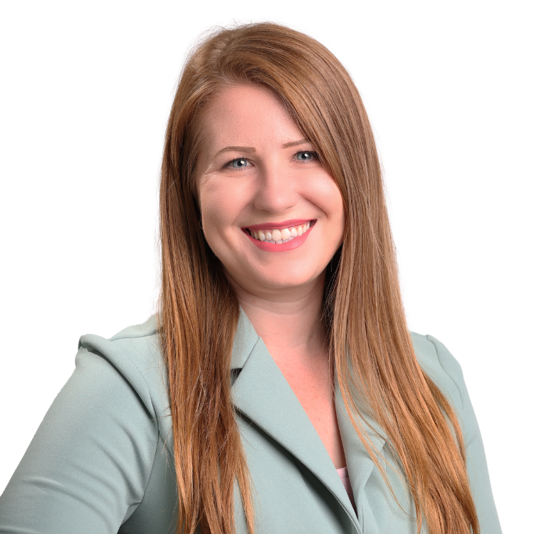 Woman with long straight red-blonde hair, wearing a light green blazer, smiling confidently in front of a white background.