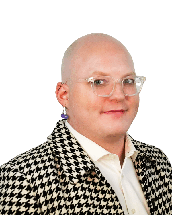Bald person with clear glasses and a bold earring, wearing a black and white houndstooth jacket over a white shirt, smiling slightly.