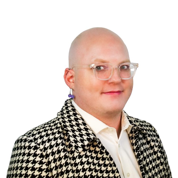 Bald person with clear glasses and a bold earring, wearing a black and white houndstooth jacket over a white shirt, smiling slightly.