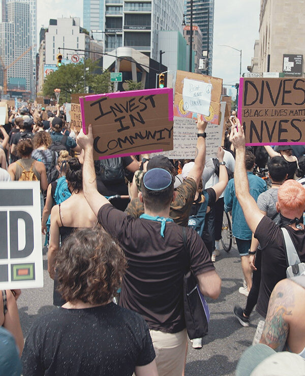 Protesters marching in a demonstration with signs calling on officials to divest from police and invest in communities.