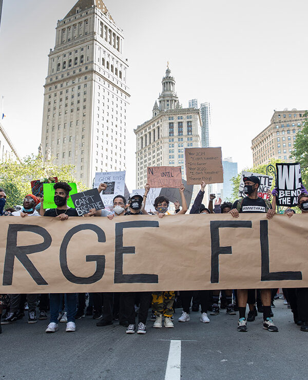 Black Lives Matter demonstrators marching with a large banner with George Floyd's name.