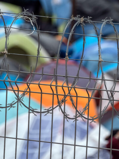 Barbed wire fence at a refugee camp for migrants and asylum seekers in Matamoros, Mexico, October 2019. Guillermo Arias for the ACLU.