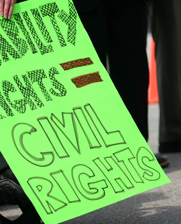 A wheelchair user holding a sign with the text "Disability rights = civil rights."