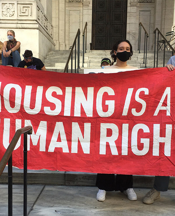 Protesters carrying a banner with the text "housing is a human right.