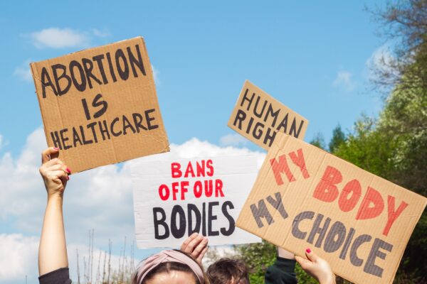 Protest signs for abortion that read "abortion is healthcare", "my body my choice," and "bans off our bodies"