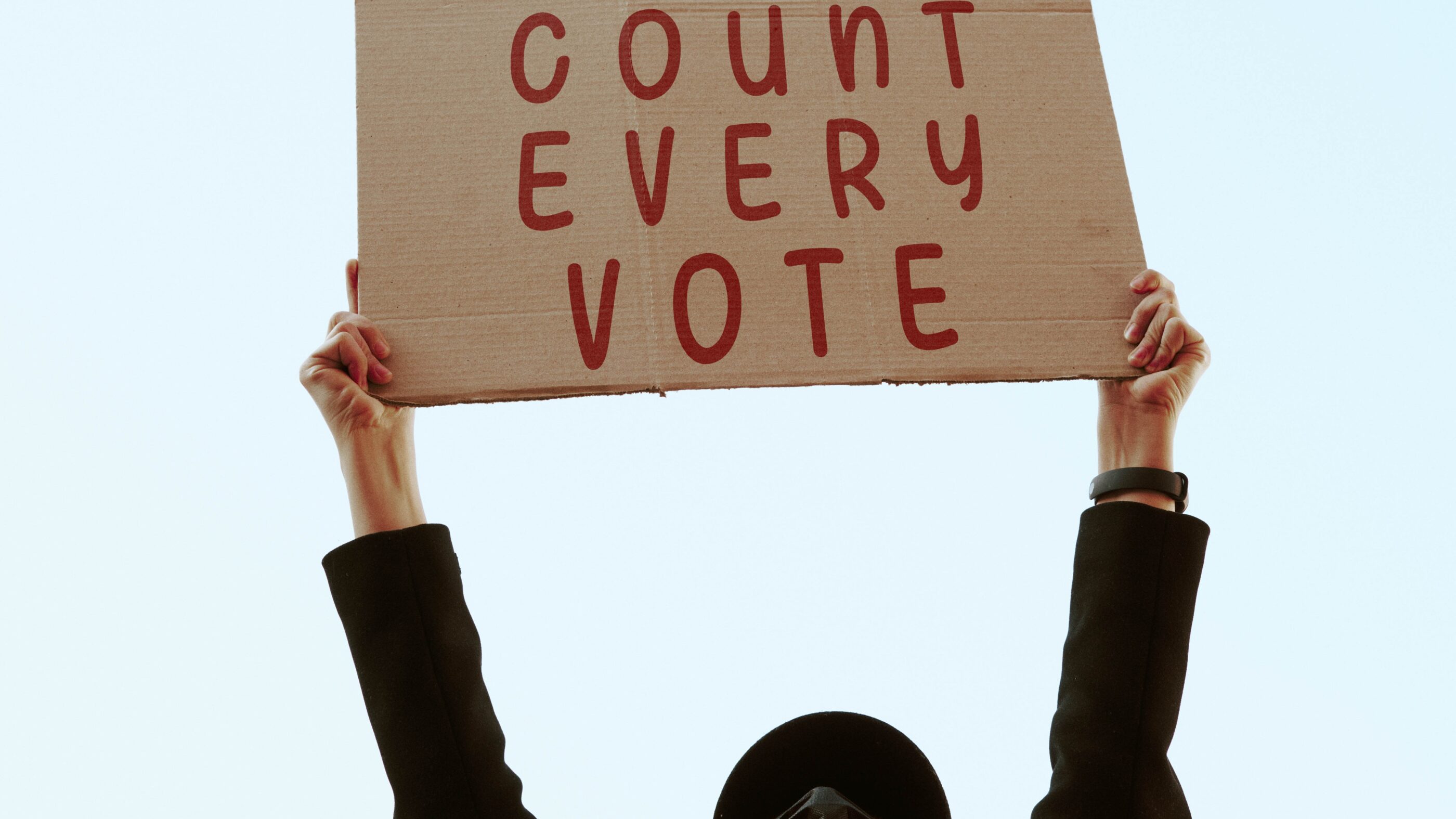 a cardboard sign that says in red text: COUNT EVERY VOTE