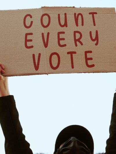 a cardboard sign that says in red text: COUNT EVERY VOTE