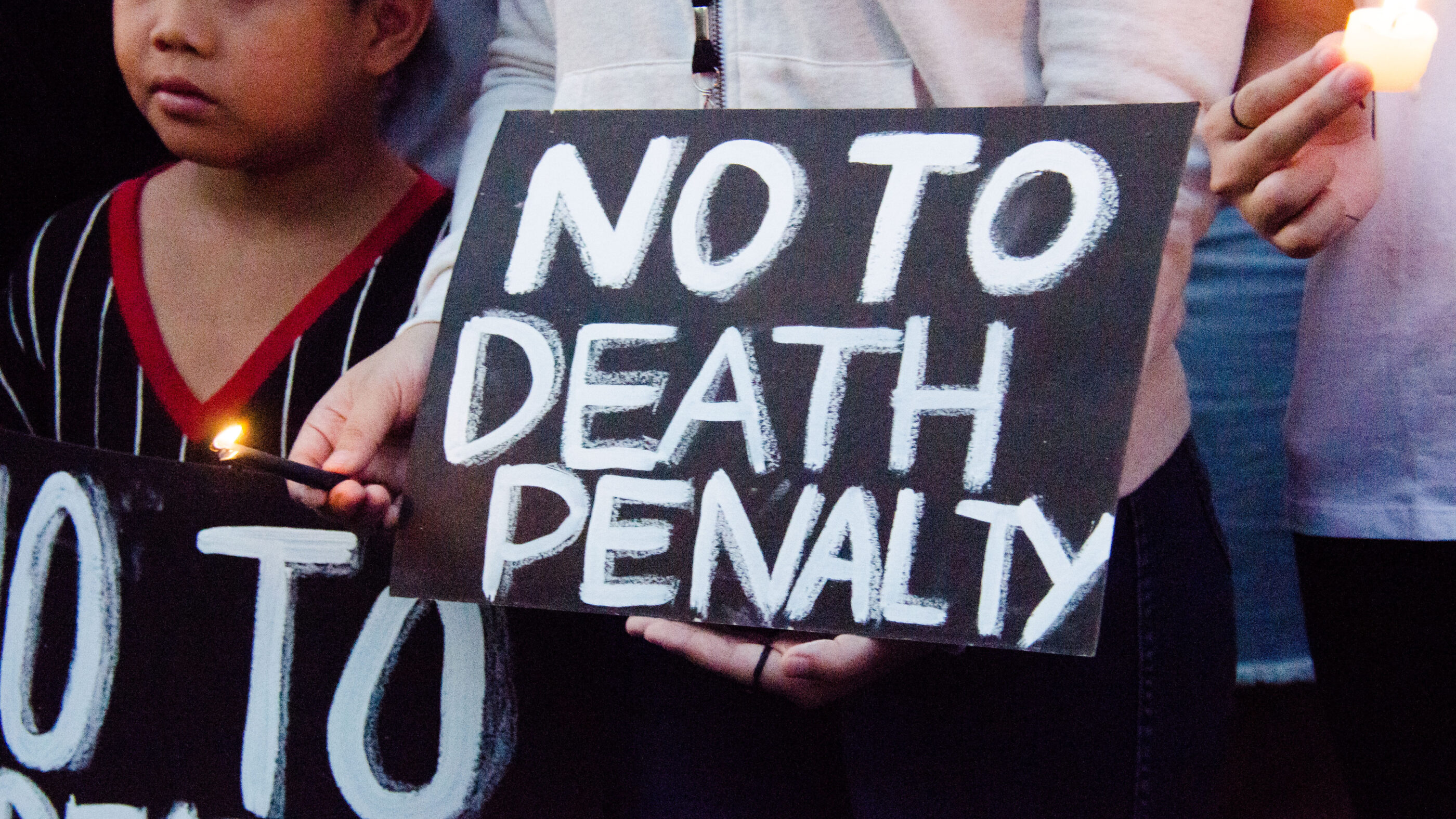 Black protest sign with white text says "NO TO DEATH PENALTY."