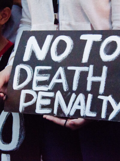 Black protest sign with white text says "NO TO DEATH PENALTY."