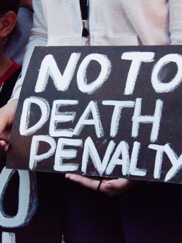 Black protest sign with white text says "NO TO DEATH PENALTY."