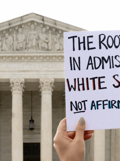 Protest sign that says "The root of bias in admissions is white supremacy, not affirmative action."