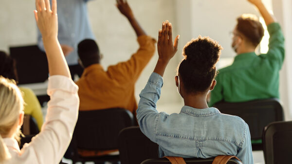 Students raising their hands in a classroom.