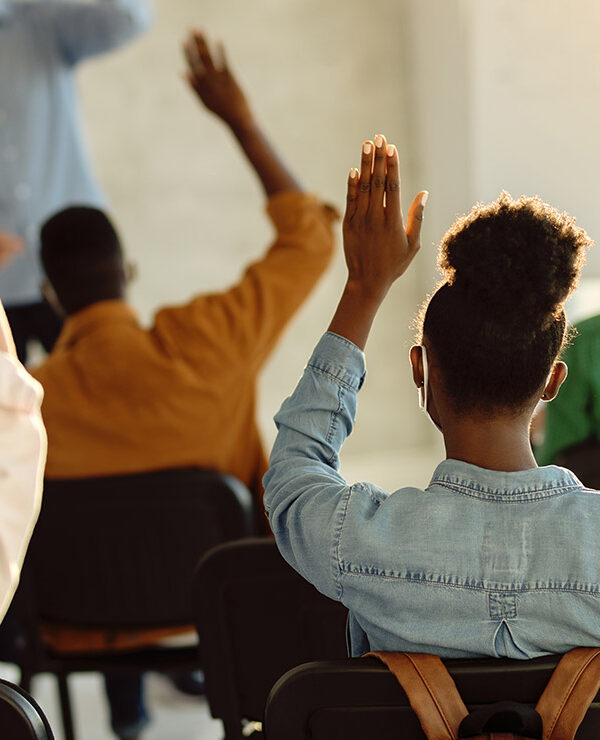 Students raising their hands in a classroom.