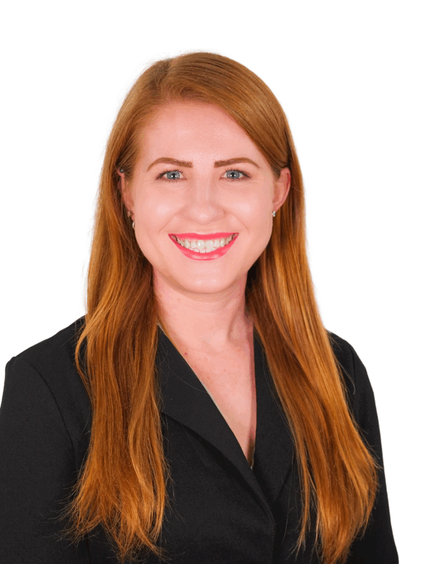 Tia in front of a white background. She is wearing a black button up. She is a white woman with red hair and blue eyes.