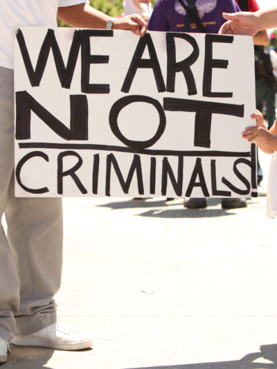 Child holding sign that reads "We are not criminals."