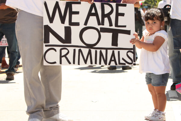 Child holding sign that reads "We are not criminals."