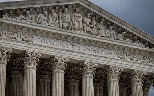 Close-up of the front of the United States Supreme Court building, showing its columns and the engraving ‘Equal Justice Under Law’ beneath detailed sculptures along the roofline.