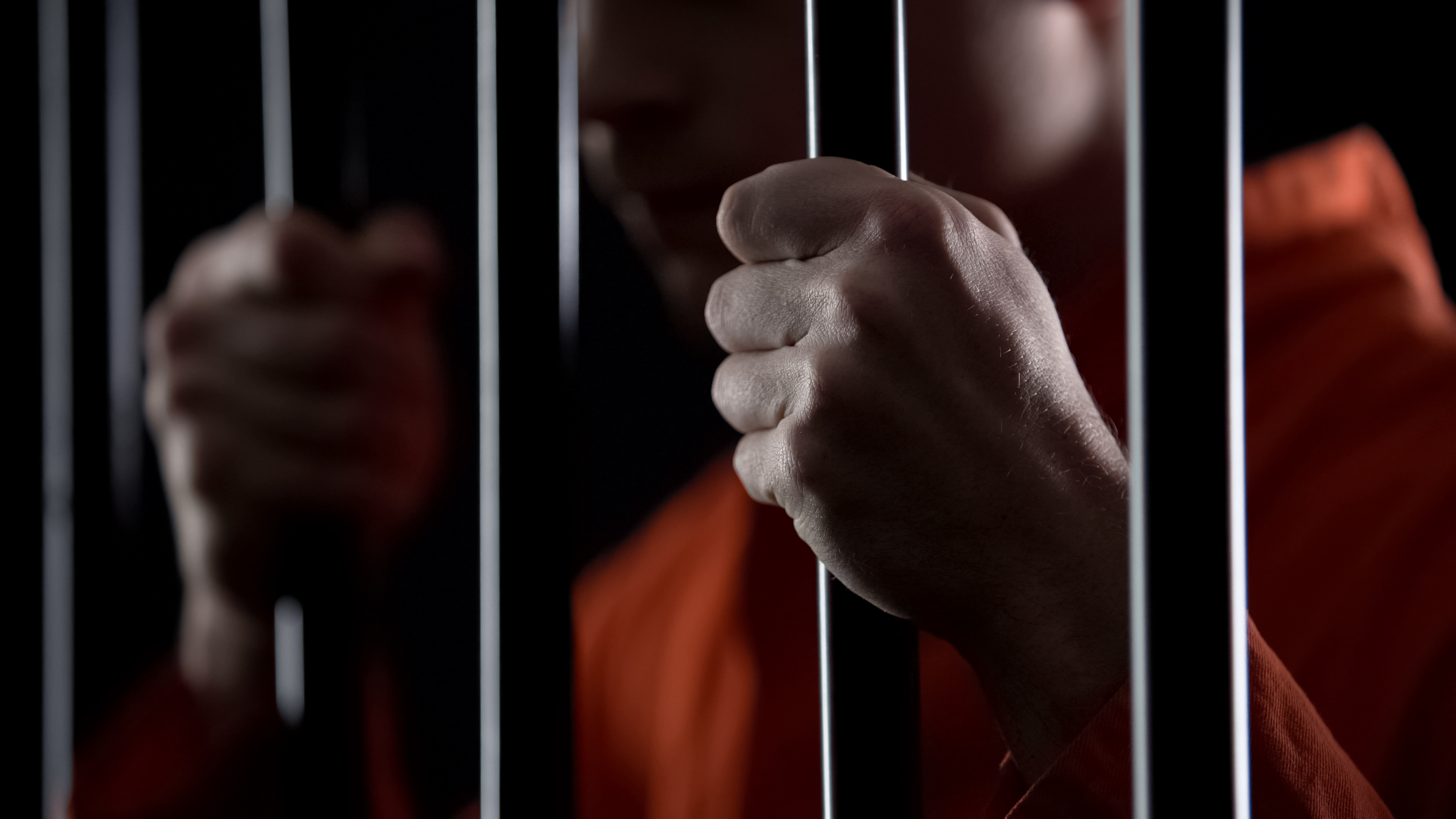 hands gripping prison bars