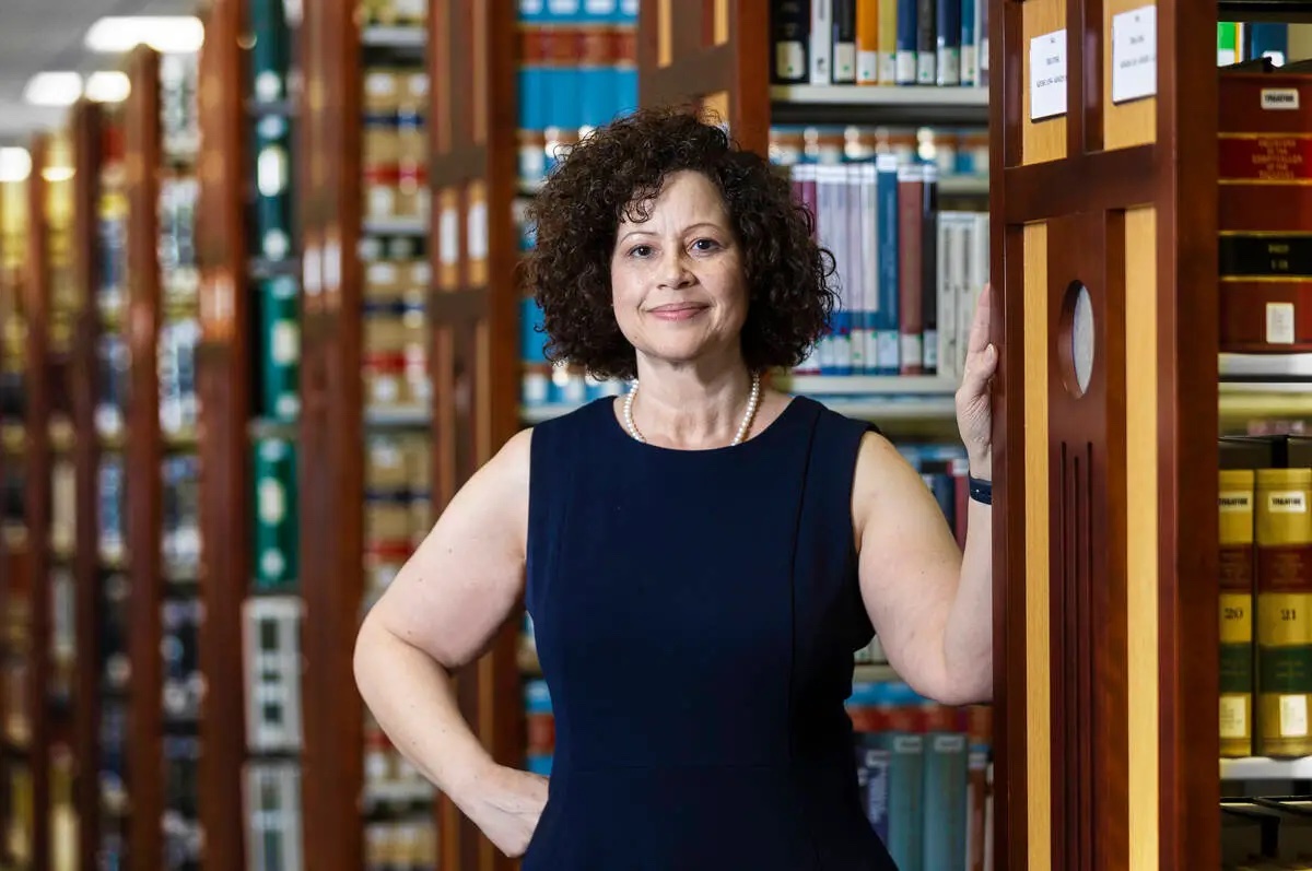 A headshot of Rachel Anderson. She is standing in a library leaning against a bookshelf.