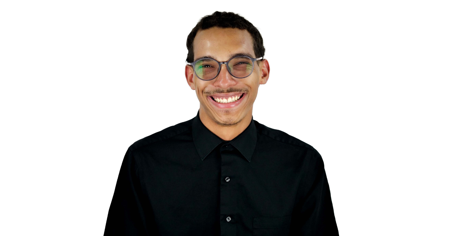 Anwar Allums in front of a white background. He is wearing glasses and a black button up shirt
