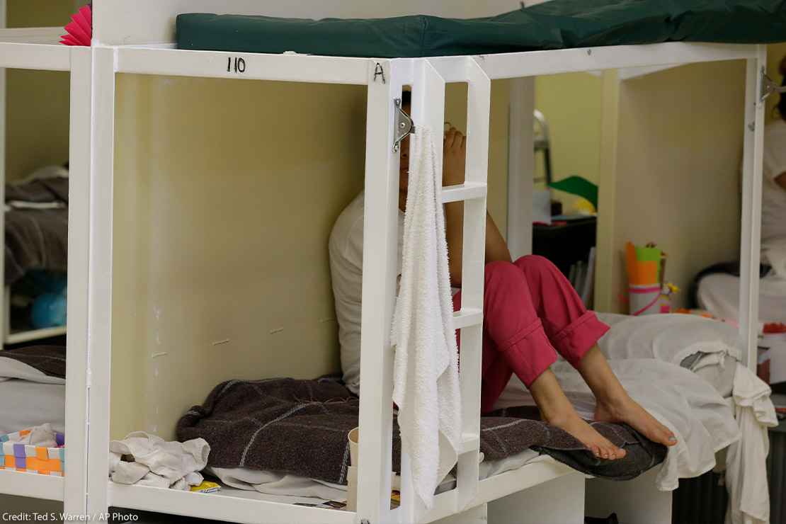A detainee sits on a bunk in a women's area at an immigration detention center.
