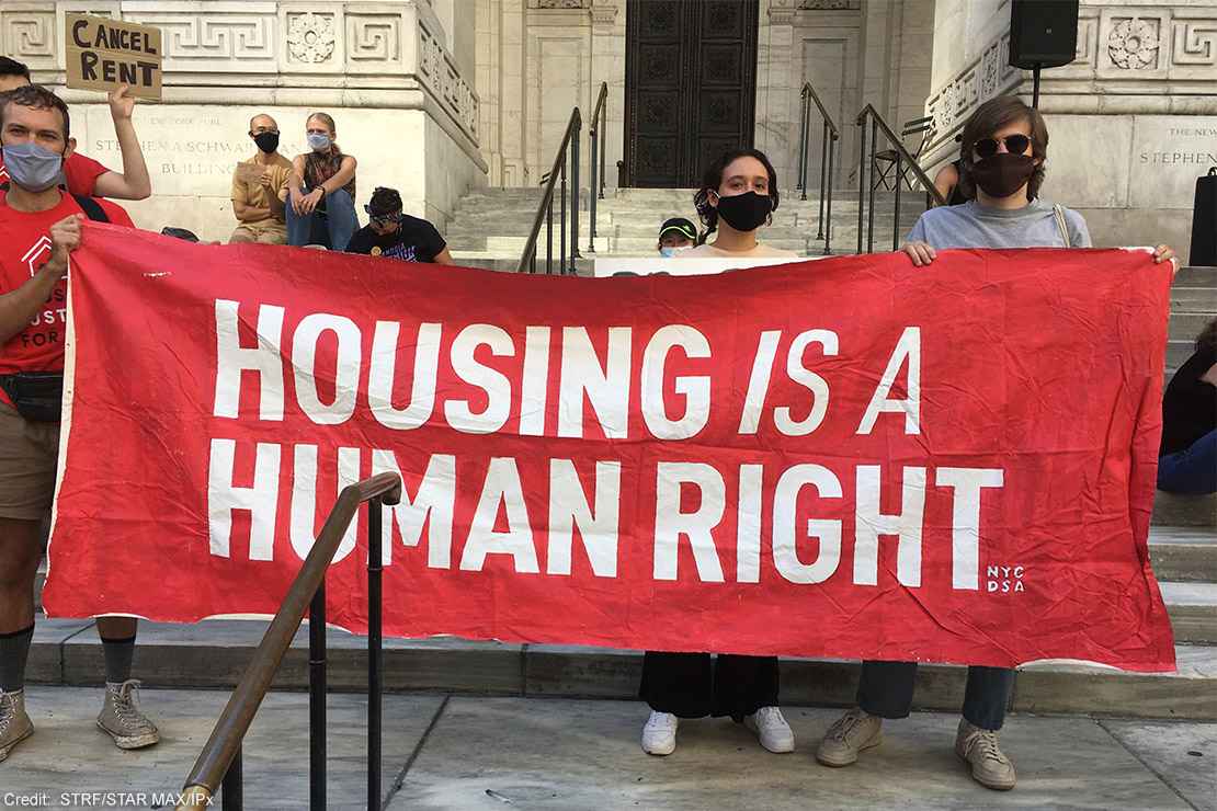 Protesters carrying a banner with the text "housing is a human right.