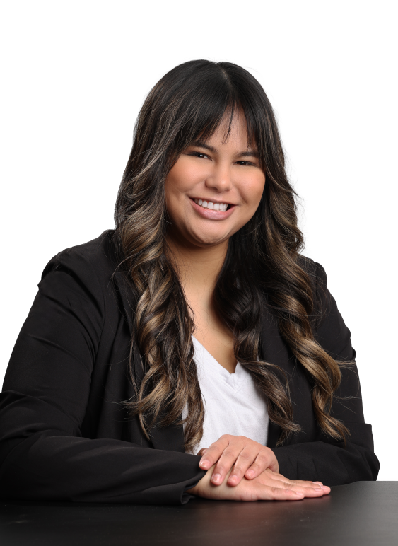 Headshot of Jordyn. She is wearing a white shirt and a black blazer. She is a brown woman with long brown hair and bangs.