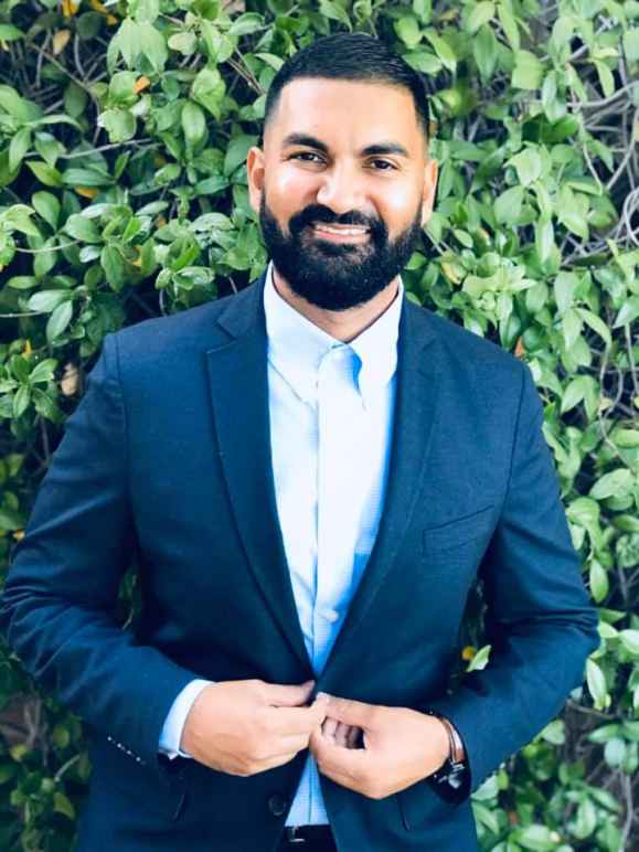 Executive Director Athar Haseebullah poses for a photo in front iof leaves