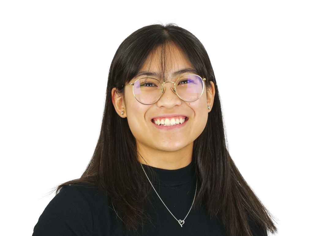 Erin in front of a white background. She is smiling and wearing glasses, a black top and gold neckalce.