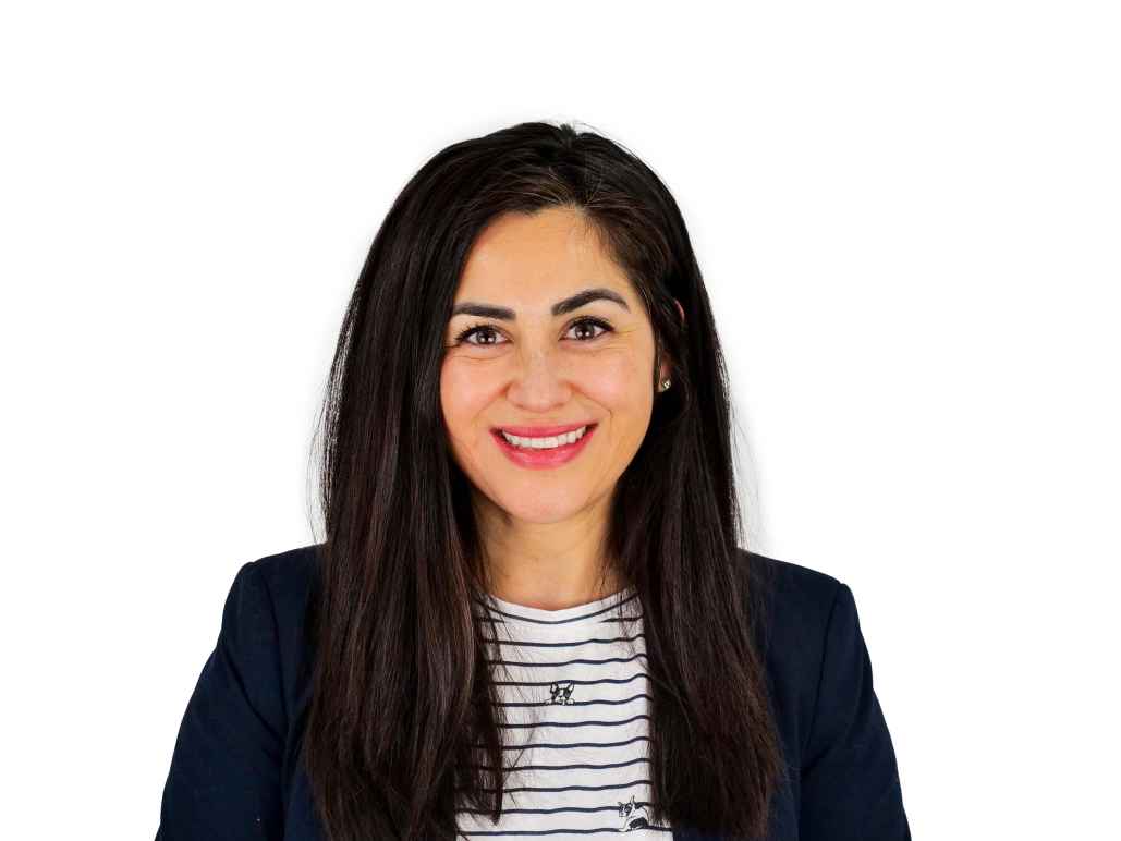 Genevieve in front of white background. She is wearing a navy blazer and black and white striped blouse.