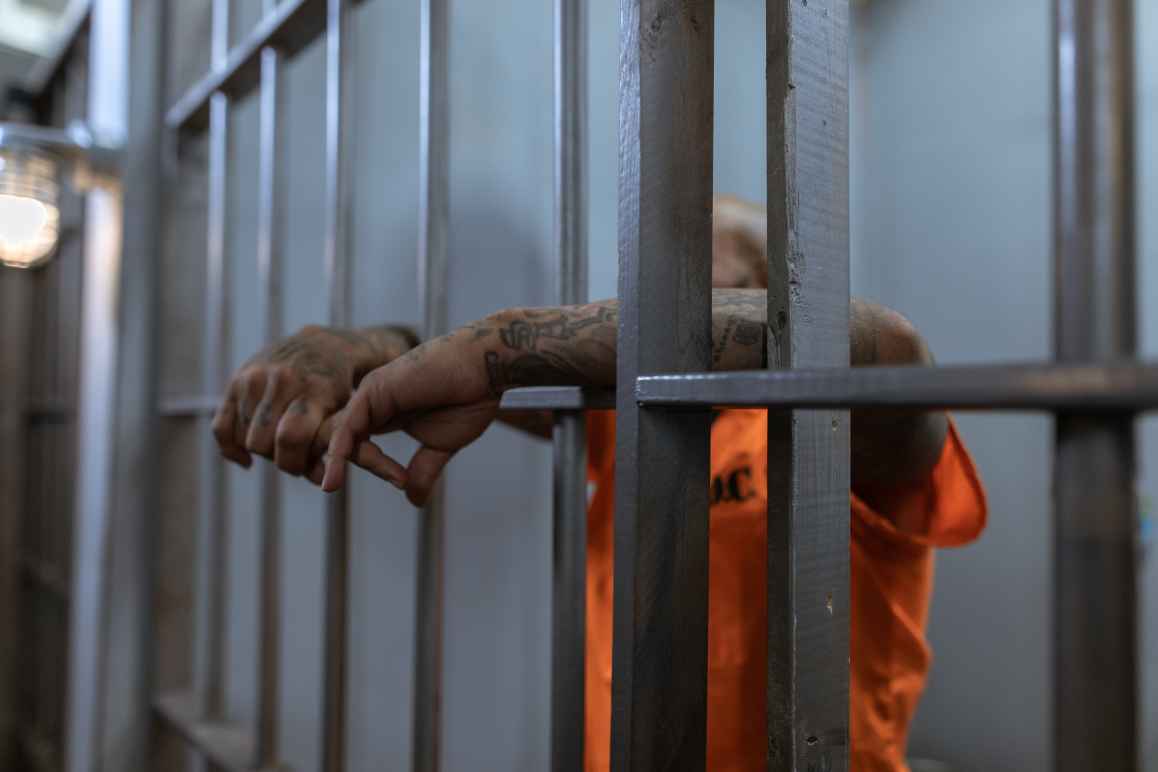 prisoner hanging arms through the bars of their cell