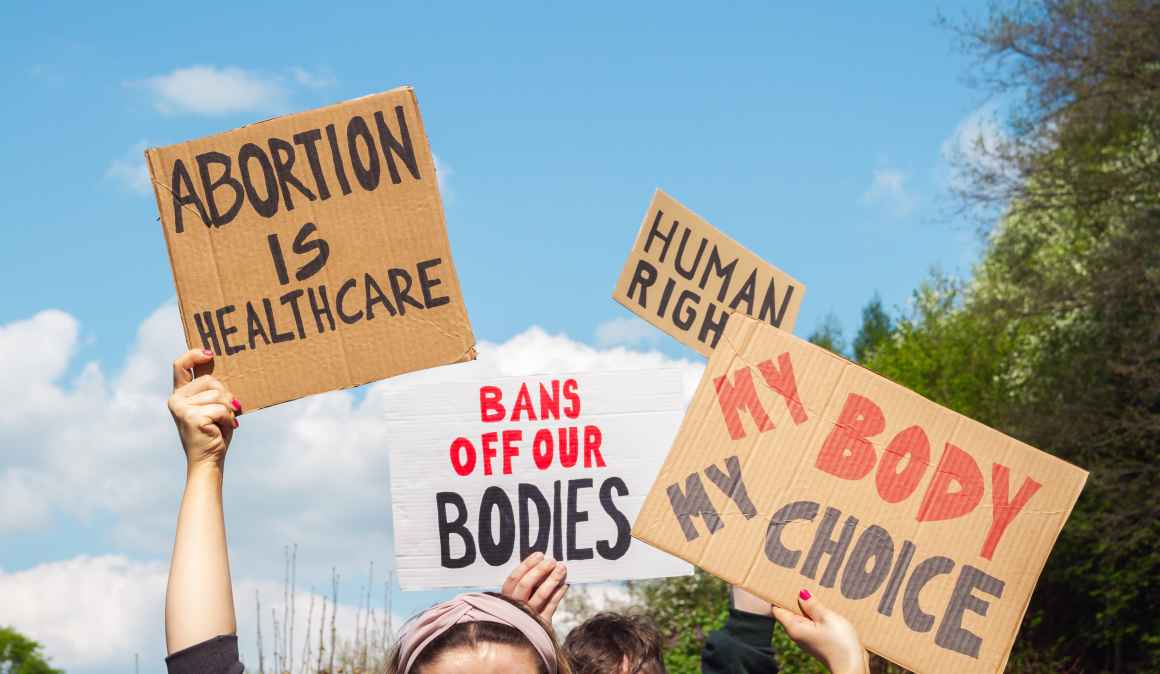 Protest signs for abortion that read "abortion is healthcare", "my body my choice," and "bans off our bodies"