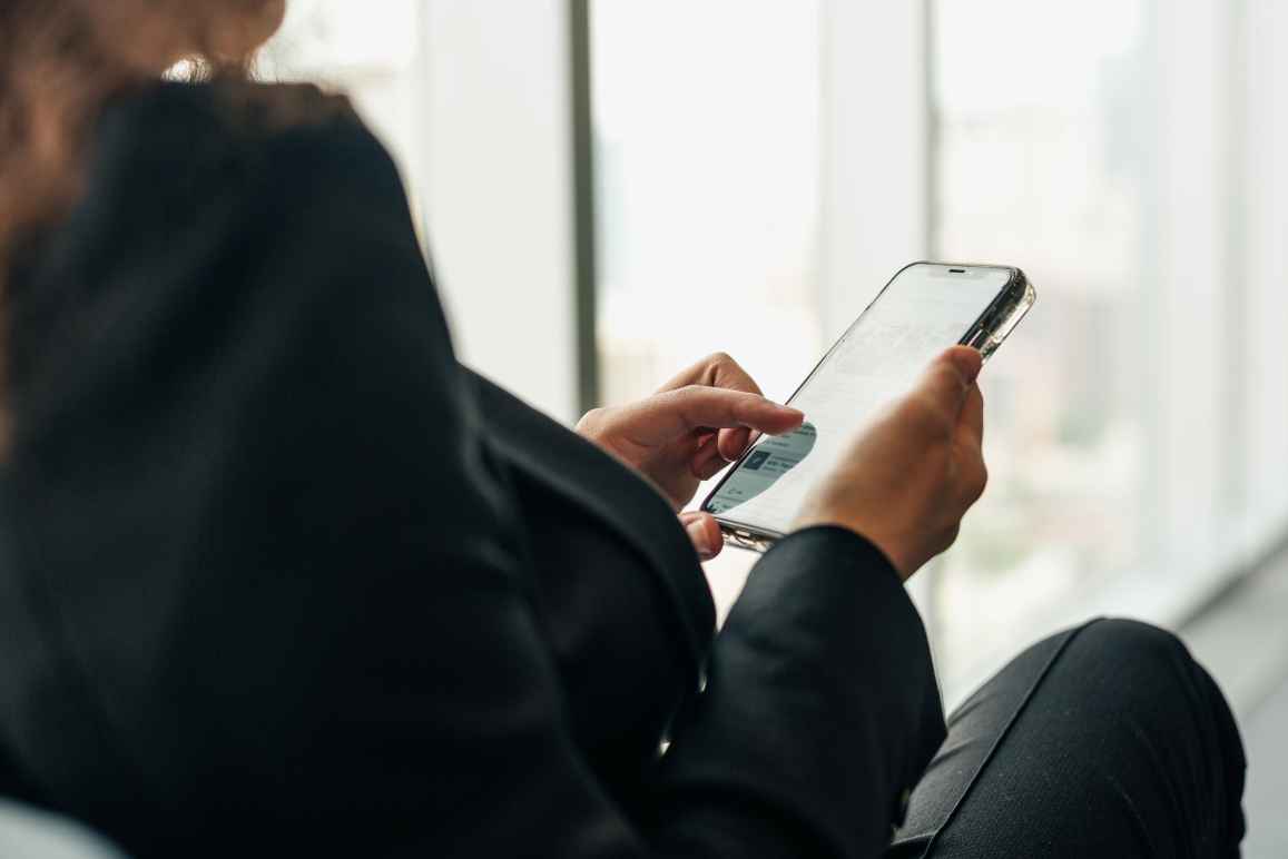 Woman holding a phone browsing Facebook