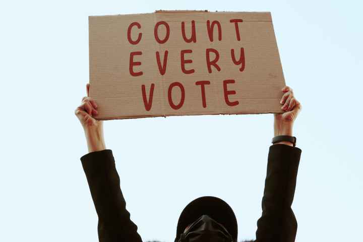a cardboard sign that says in red text: COUNT EVERY VOTE