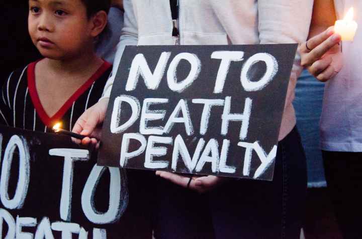 Black protest sign with white text says "NO TO DEATH PENALTY."
