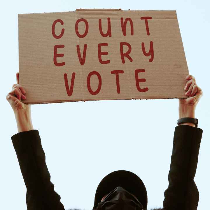 a cardboard sign that says in red text: COUNT EVERY VOTE