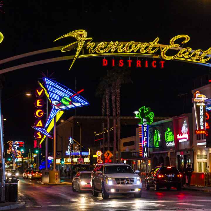 Fremont Street at night with cars driving under the overhead sign