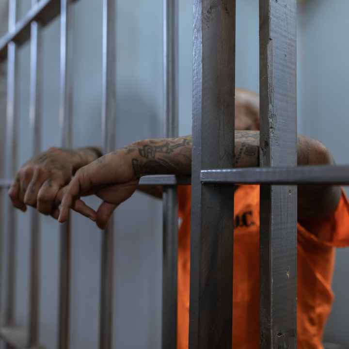 prisoner hanging arms through the bars of their cell