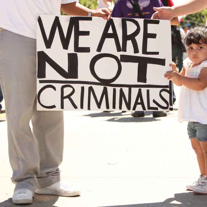 Child holding sign that reads "We are not criminals."