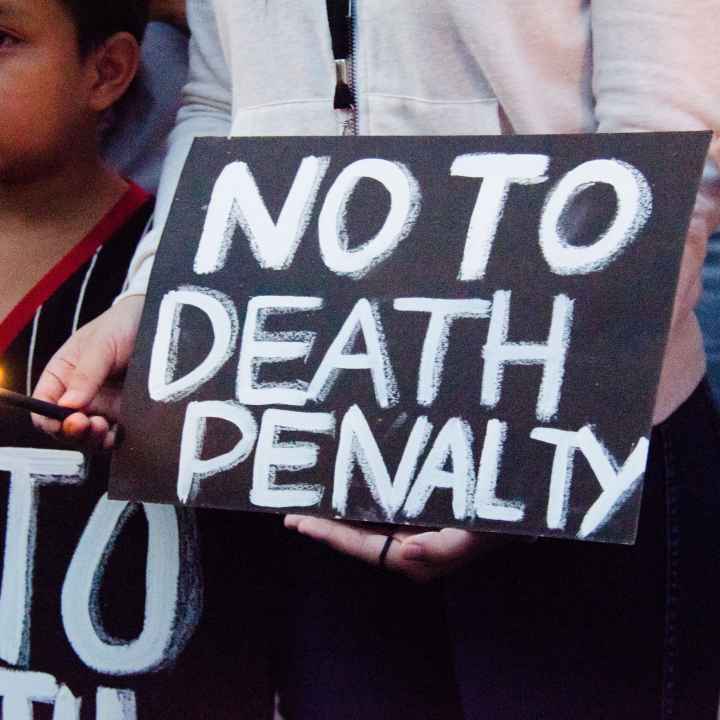 Black protest sign with white text says "NO TO DEATH PENALTY."